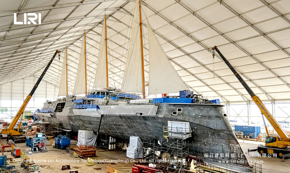 Large vessel under a white clear-span tent with cranes inside