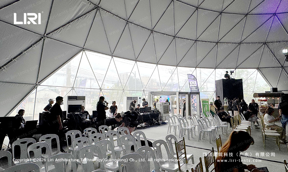 Rows of spectator chairs beside event production equipment inside a geodesic dome
