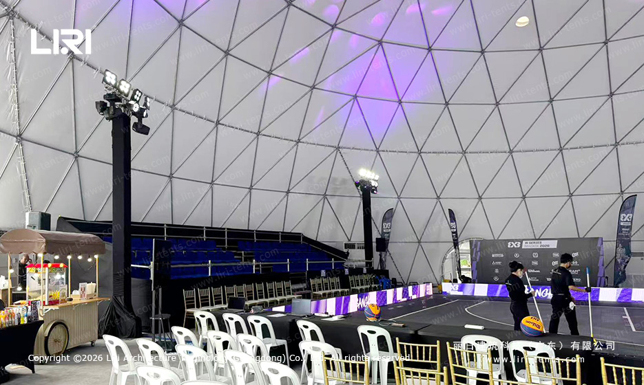Court-side chairs, tiered seating and lighting towers inside the basketball event dome
