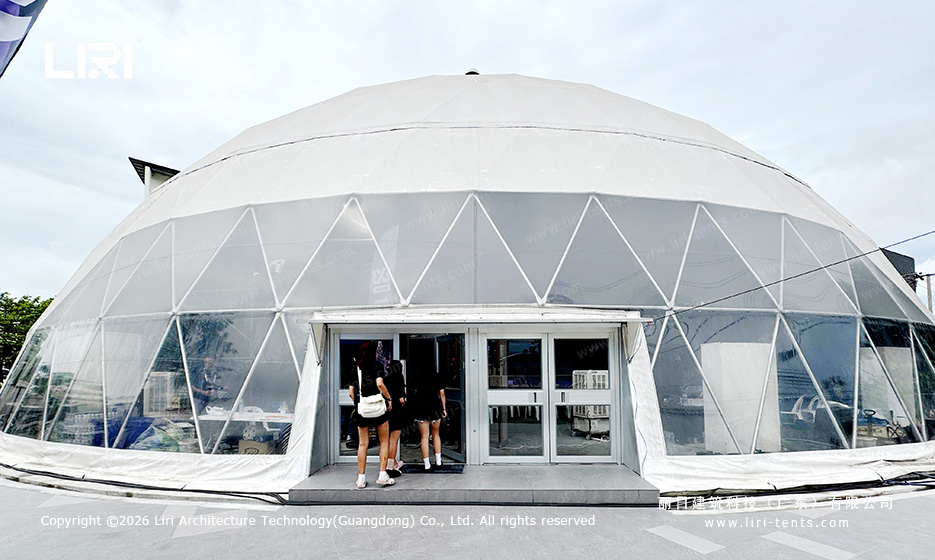 Double-door entrance set into the transparent lower perimeter of the white geodesic dome