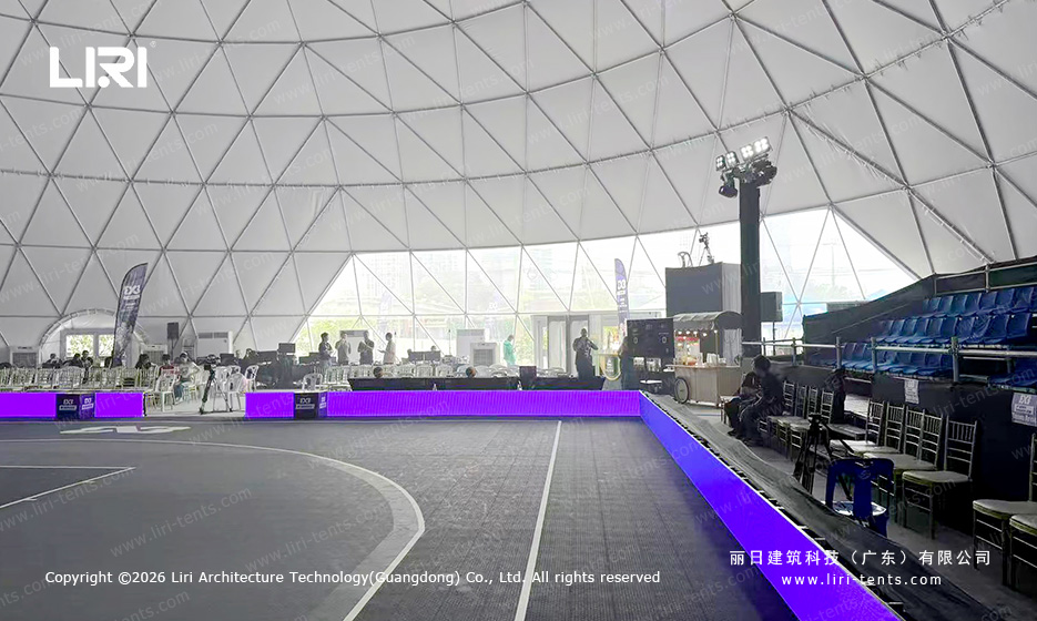 Wide view across the basketball court toward transparent dome panels and spectator seating