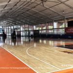 Basketball court tent interior with wooden flooring and transparent sidewalls