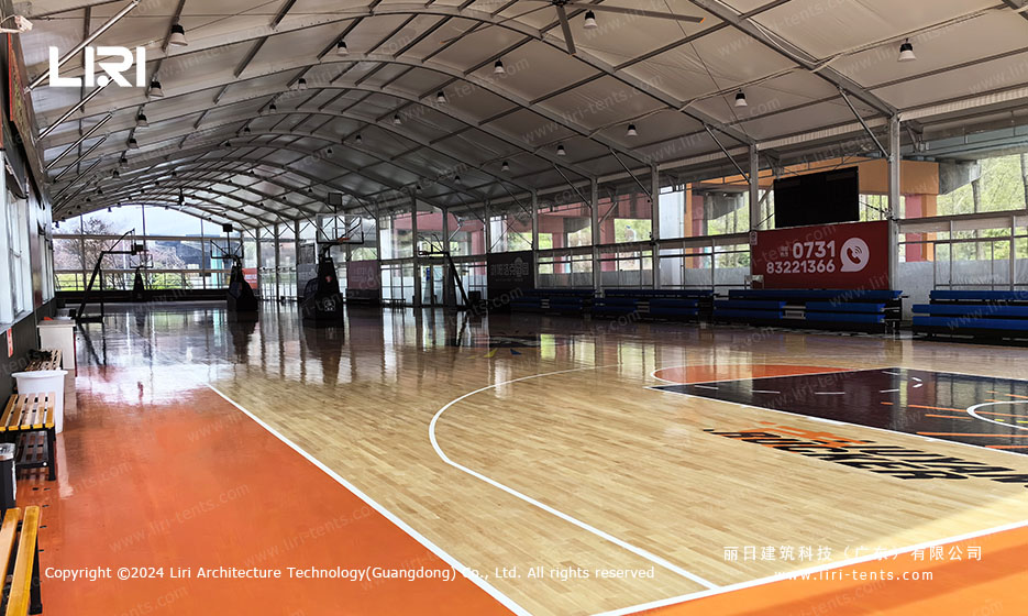 Basketball court tent interior with wooden flooring and transparent sidewalls
