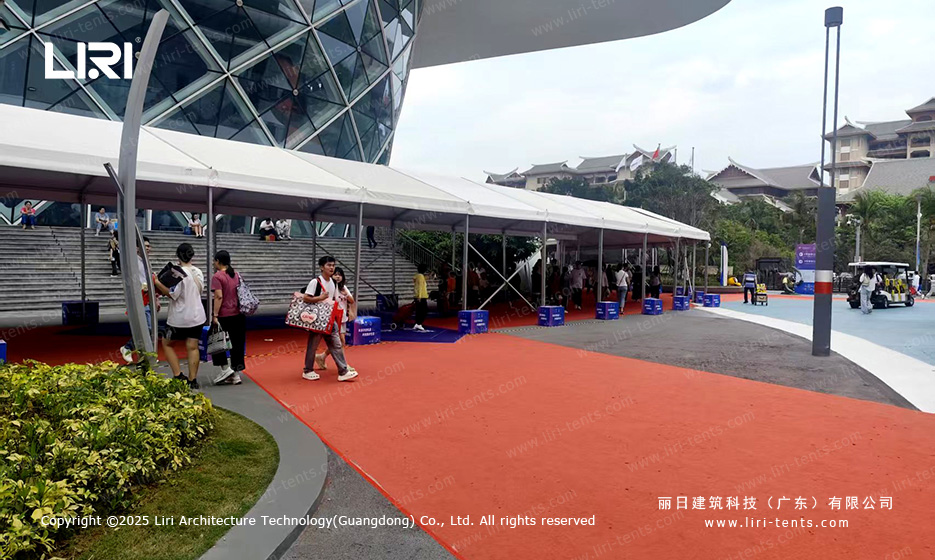 Long white clear span walkway canopy tent connecting a glass dome venue to outdoor exhibition area