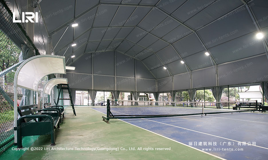 Exterior front view of multi-arch tennis hall tent near residential buildings