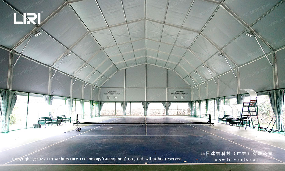 Wide interior view of multi-arch tennis hall tent showing full court