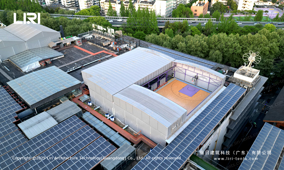 Aerial view of purple twin retractable basketball court tent on a city rooftop between solar panel arrays
