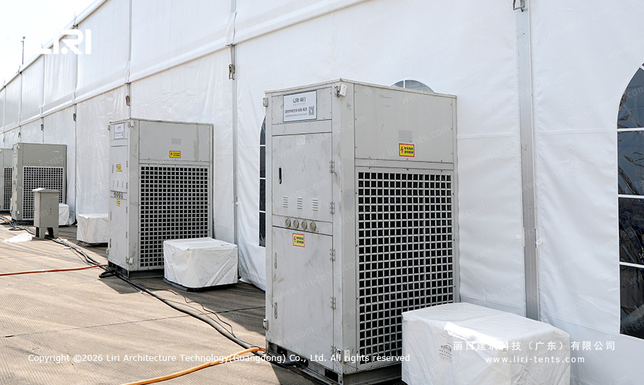 Outdoor industrial HVAC units placed against the back wall of a white clear span event tent at a race track hospitality area