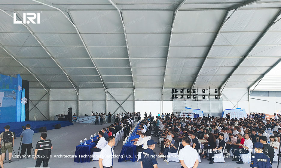 Full house crowd inside a clear span event tent during a Shenzhen opening ceremony with stage on the left