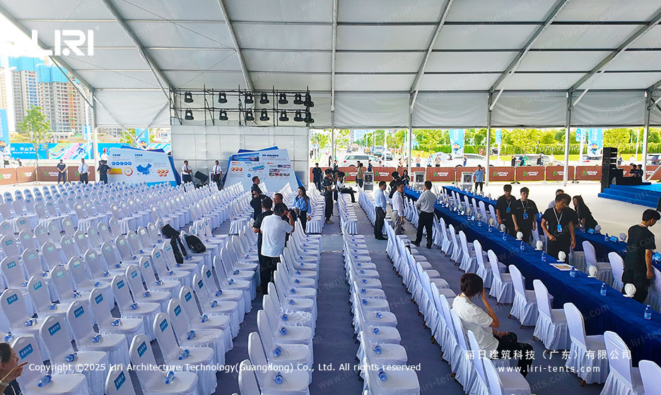 Rows of white guest chairs facing an LED stage backdrop inside a large clear span ceremony tent in Shenzhen
